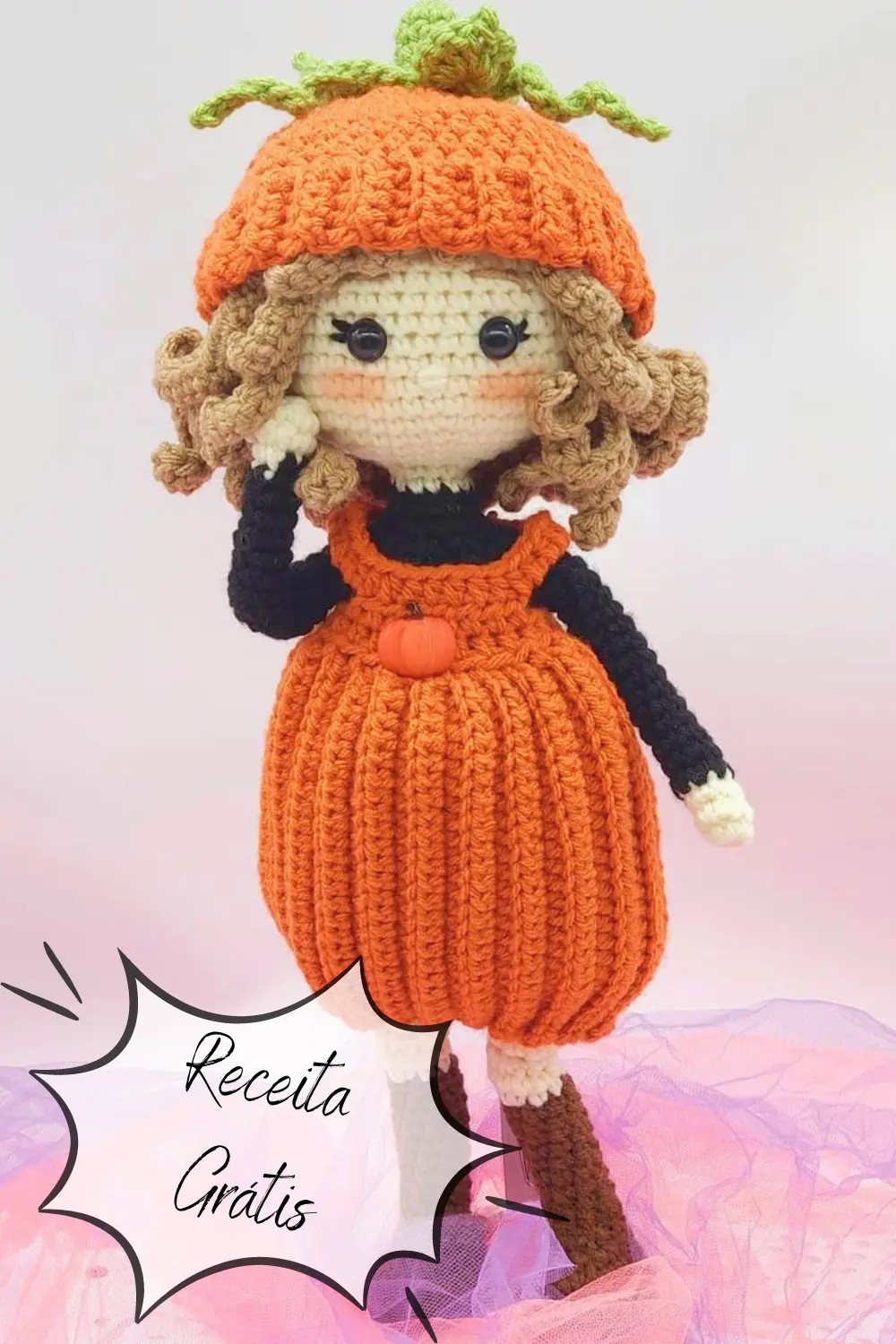 Uma boneca de crochê com roupa laranja e segurando abóboras