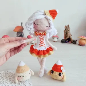 Boneca Candy Corn em amigurumi com cabelo branco, vestido laranja e mini personagens temáticos