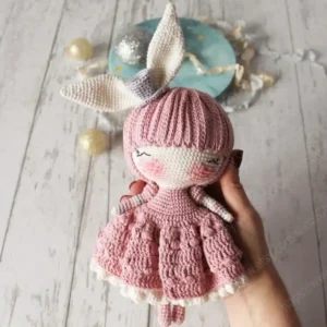 Boneca coelhinha em amigurumi com orelhas longas, vestido rosa rodado e detalhes brancos