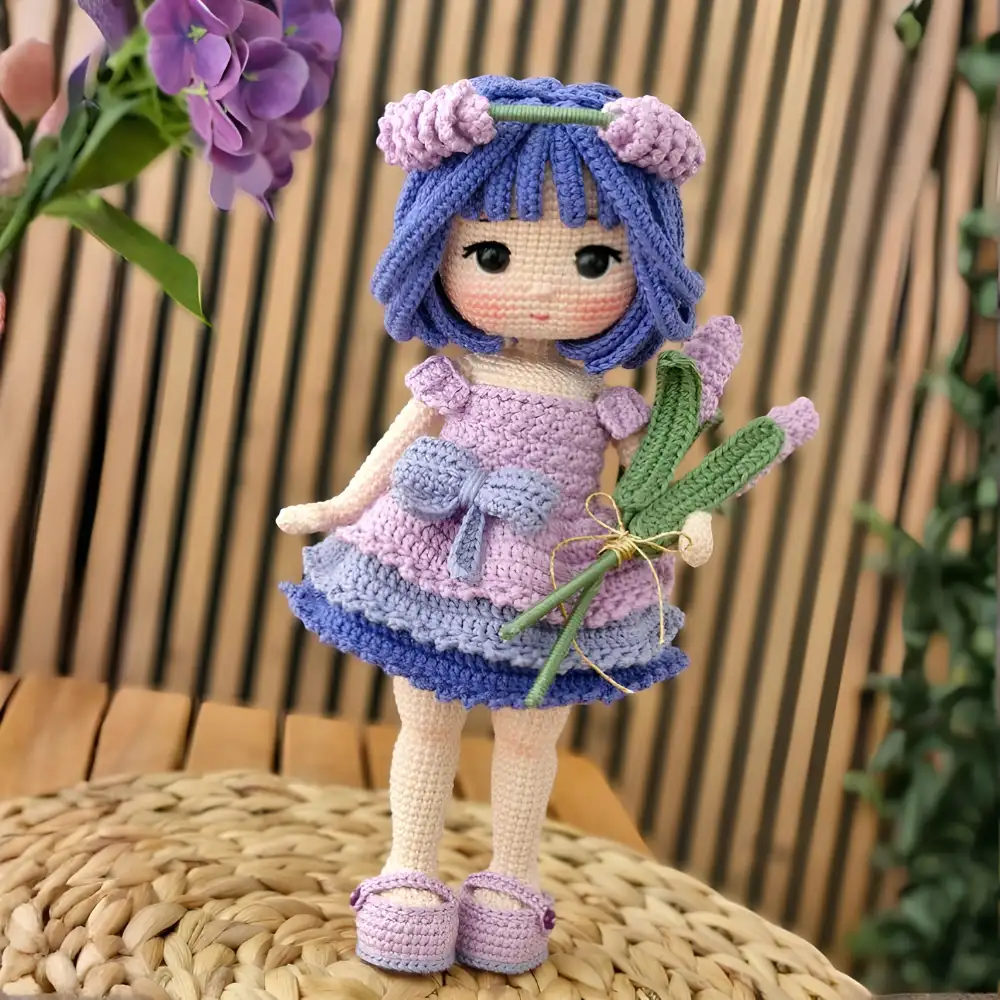 Boneca em amigurumi com cabelos roxos, vestido lilás e rosa e ramos de flores lilás