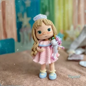 Boneca princesa em amigurumi com cabelos longos, vestido rosa, tiara e pequeno unicórnio branco