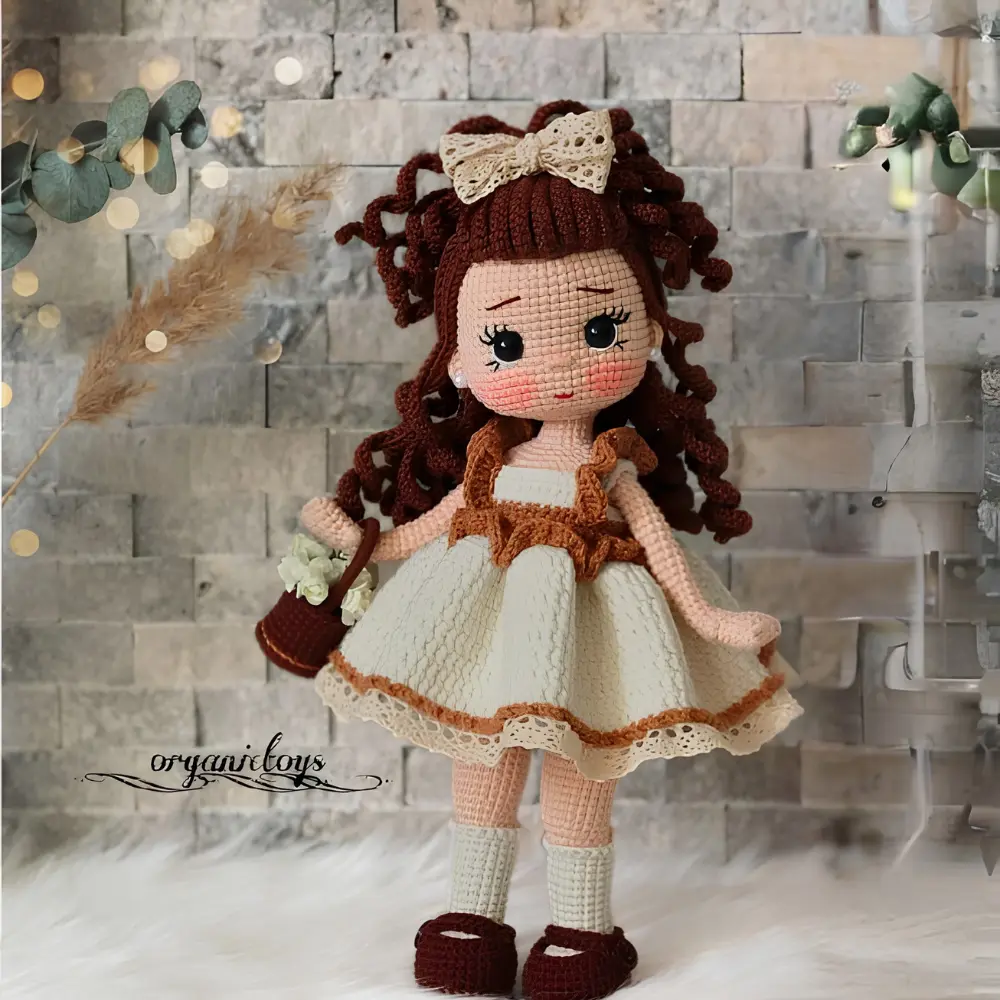 Boneca em amigurumi com cabelos cacheados, vestido creme, laço e bolsinha marrom