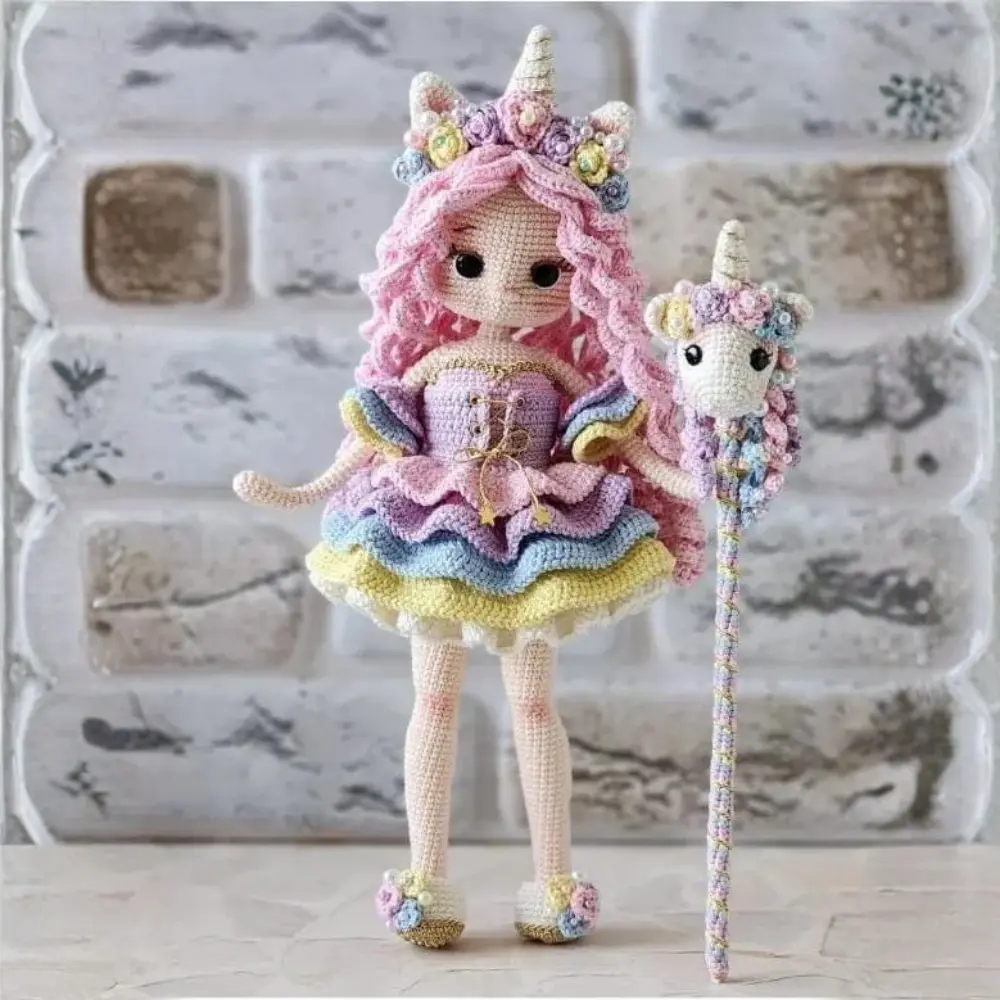 Boneca unicórnio em amigurumi com cabelos rosa, vestido pastel, chifre dourado e cajado de unicórnio