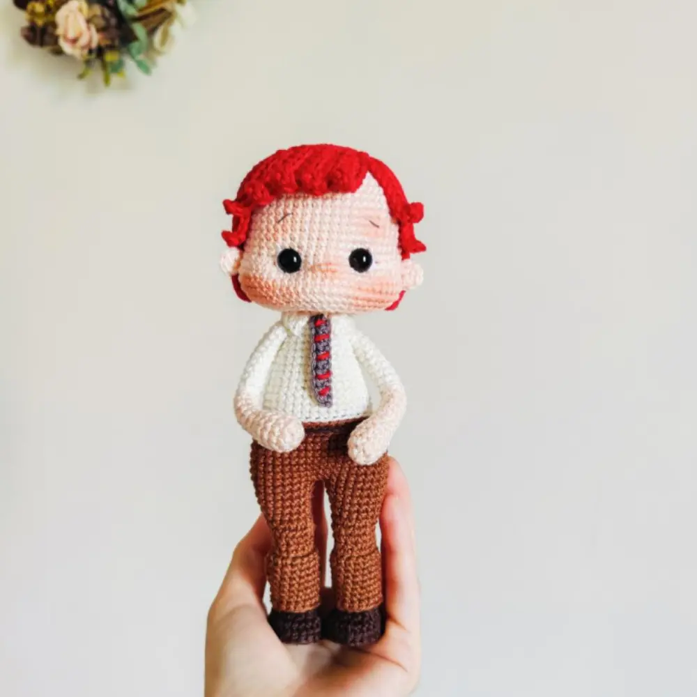 Boneco ruivo em amigurumi com camisa branca, gravata listrada e calça marrom