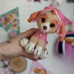 Cachorrinha em amigurumi bege com roupa rosa, orelhas caramelo e gorro de aviadora