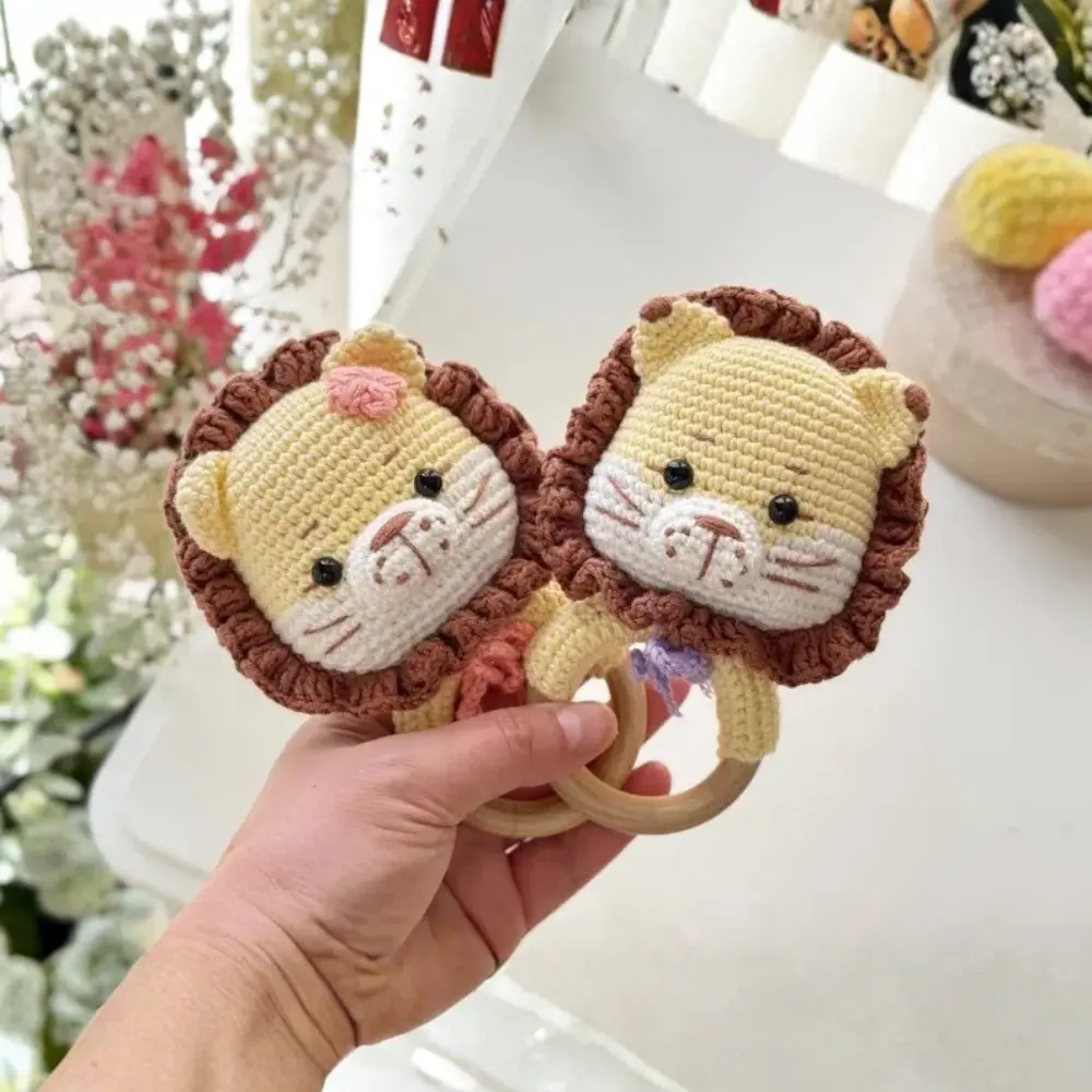 Dois chocalhos de leãozinho em amigurumi bege com juba marrom e argolas de madeira