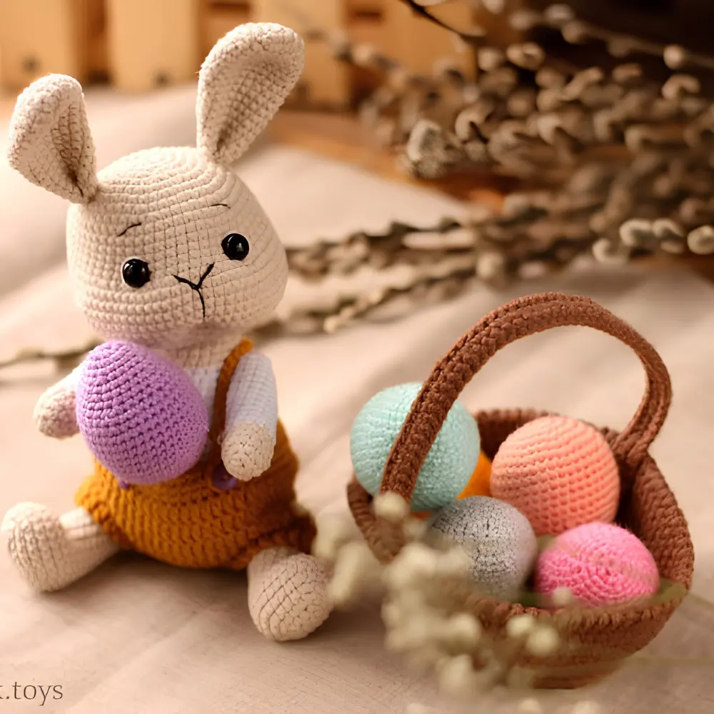 Coelhinho bege em amigurumi com roupa mostarda segurando novelo lilás