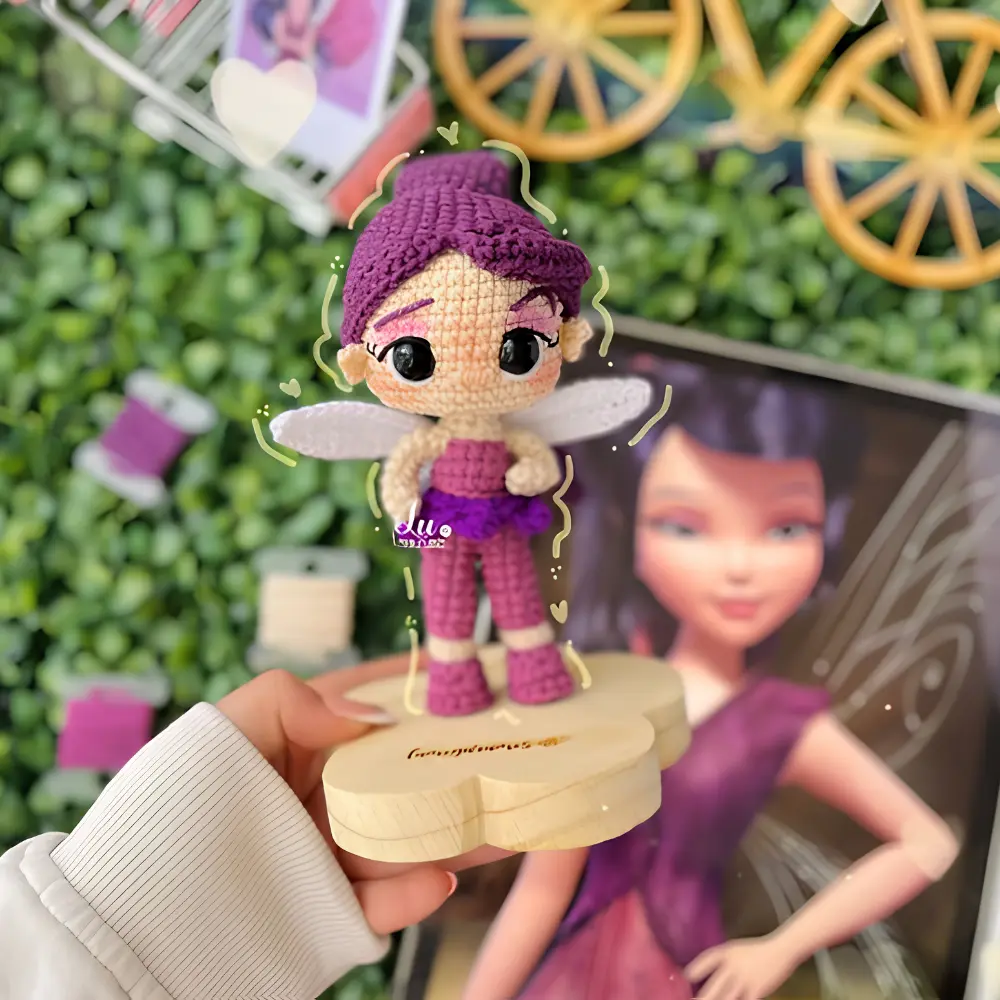 Fadinha em amigurumi com cabelos roxos, roupa rosa e roxa e asas claras