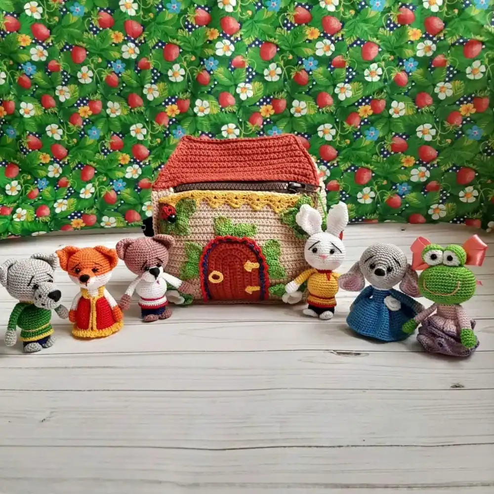 Casinha em crochê com seis animais em amigurumi coloridos posicionados ao redor