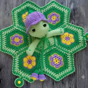 Naninha de tartaruguinha em crochê verde com gorrinho lilás e manta com flores amarelas e roxas