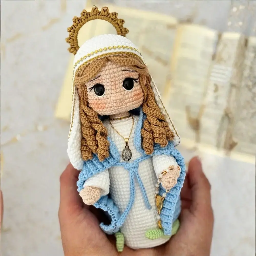 Nossa Senhora em amigurumi com vestido branco, manto azul, véu branco, auréola e terço