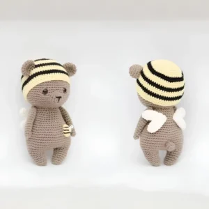 Ursinho em amigurumi com gorro amarelo e preto, asas brancas e pequena abelhinha